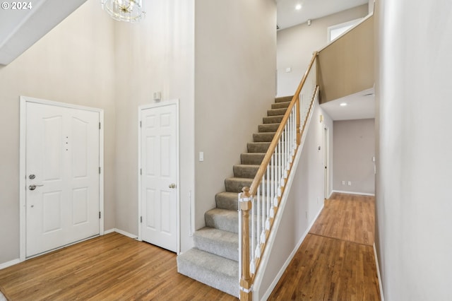 entrance foyer with hardwood / wood-style floors, a high ceiling, and an inviting chandelier