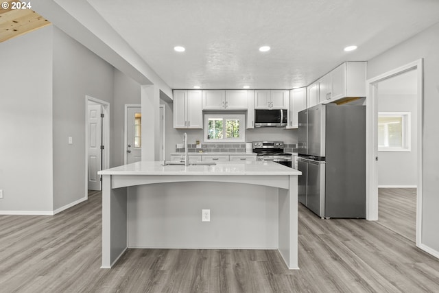 kitchen with appliances with stainless steel finishes, light hardwood / wood-style flooring, sink, and white cabinets