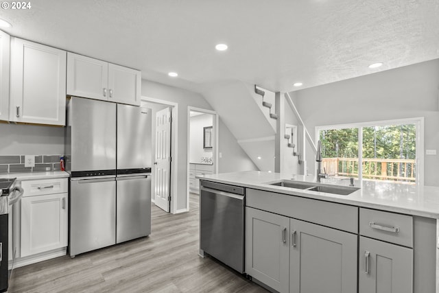 kitchen featuring appliances with stainless steel finishes, light wood-type flooring, white cabinets, gray cabinets, and sink