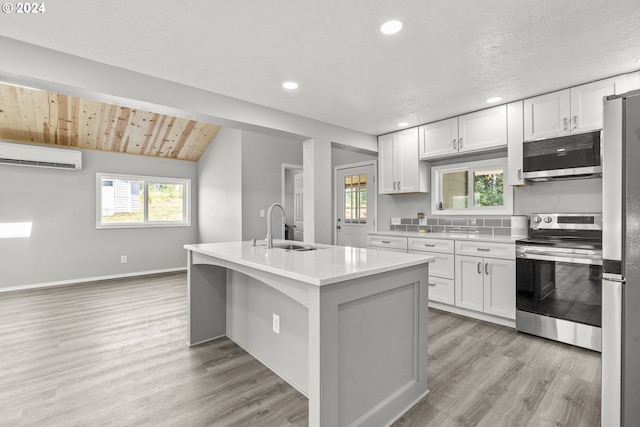 kitchen featuring sink, white cabinetry, a wall mounted air conditioner, and stainless steel appliances