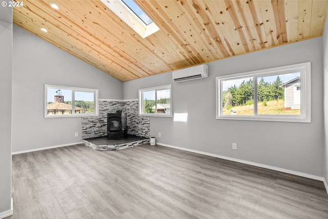 unfurnished living room with an AC wall unit, wood ceiling, hardwood / wood-style floors, a wood stove, and lofted ceiling with skylight