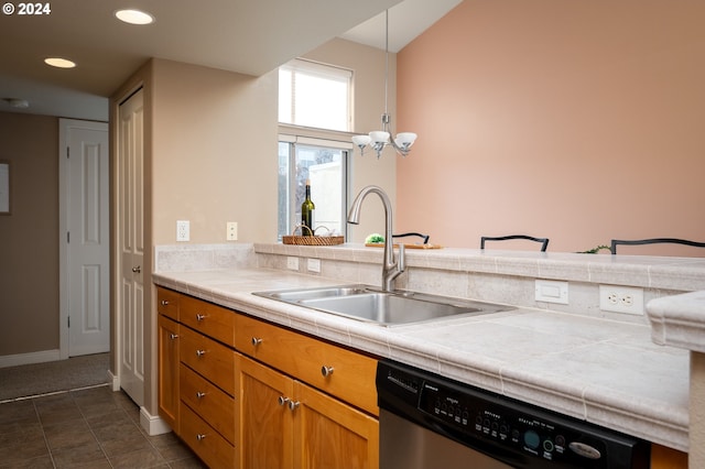 kitchen featuring stainless steel dishwasher, tile countertops, sink, and hanging light fixtures