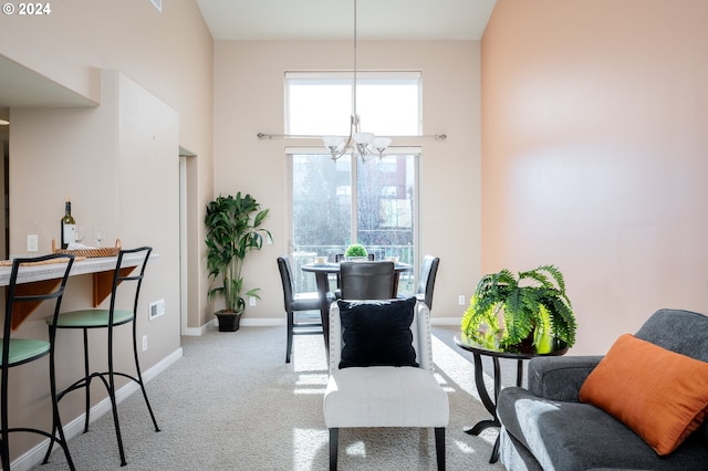 dining room featuring light colored carpet, a high ceiling, and an inviting chandelier