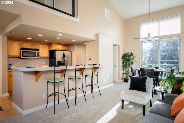 kitchen with high vaulted ceiling, decorative backsplash, decorative light fixtures, stainless steel appliances, and a chandelier