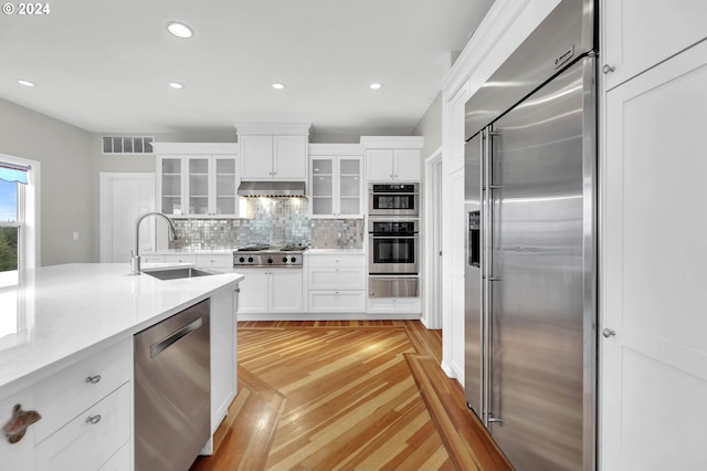 kitchen with stainless steel appliances, visible vents, backsplash, a sink, and under cabinet range hood