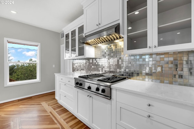 kitchen with tasteful backsplash, stainless steel gas stovetop, white cabinetry, and exhaust hood