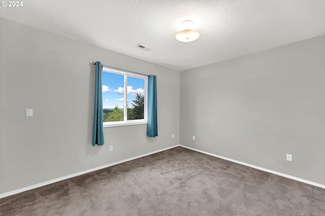 carpeted spare room with baseboards, visible vents, and a textured ceiling