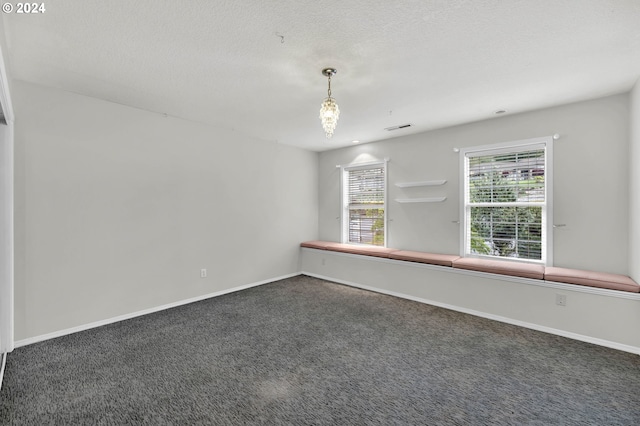 spare room with baseboards, visible vents, dark carpet, and a textured ceiling