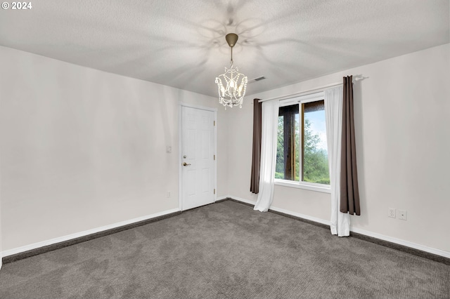 unfurnished room featuring a chandelier, dark carpet, a textured ceiling, and baseboards