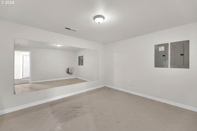 empty room featuring electric panel, visible vents, concrete flooring, and a textured ceiling