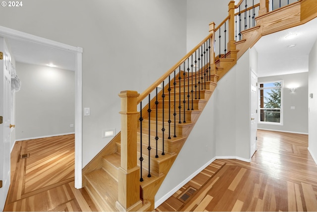 stairs featuring a towering ceiling, parquet flooring, visible vents, and baseboards