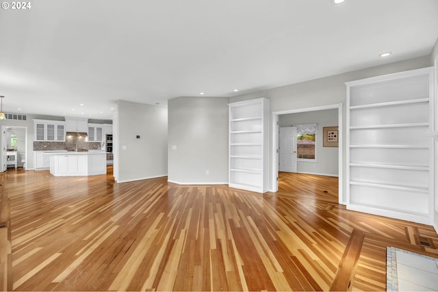 unfurnished living room featuring baseboards, light wood-type flooring, visible vents, and recessed lighting