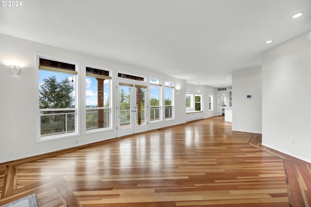 unfurnished living room with light wood-type flooring, baseboards, and recessed lighting