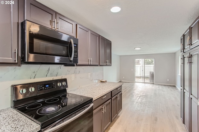 kitchen featuring dark brown cabinets, light stone counters, black electric range, tasteful backsplash, and light hardwood / wood-style flooring