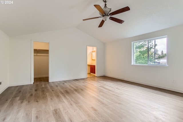 unfurnished bedroom featuring vaulted ceiling, light hardwood / wood-style flooring, ensuite bath, a walk in closet, and ceiling fan