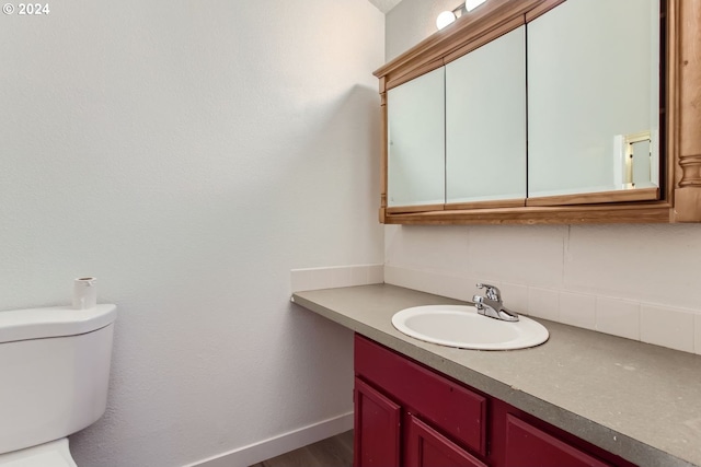 bathroom with wood-type flooring, vanity, and toilet