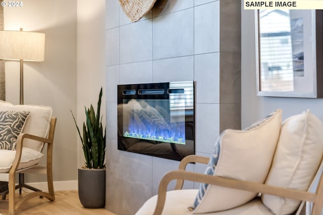 living area featuring baseboards, wood finished floors, and a tiled fireplace