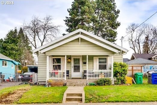 bungalow featuring covered porch and a front lawn