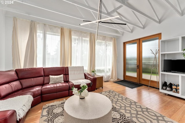 sunroom featuring lofted ceiling with beams, a wealth of natural light, and french doors