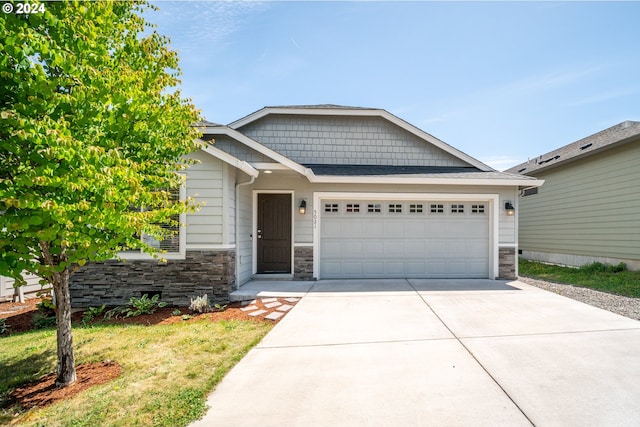 craftsman inspired home featuring a garage and a front lawn