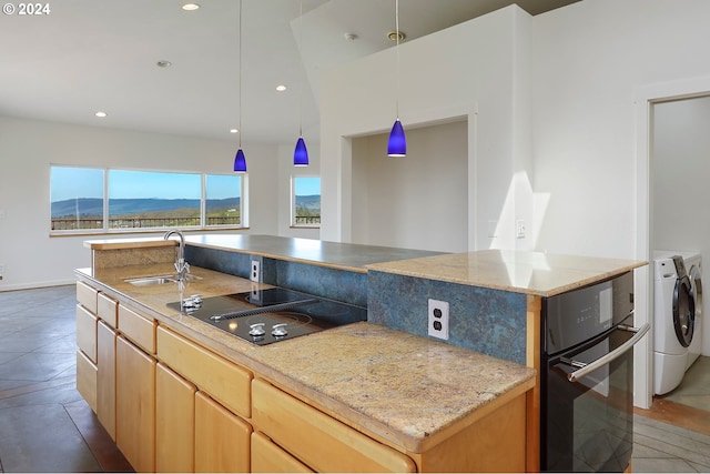 kitchen featuring a center island with sink, black electric stovetop, a mountain view, a sink, and separate washer and dryer