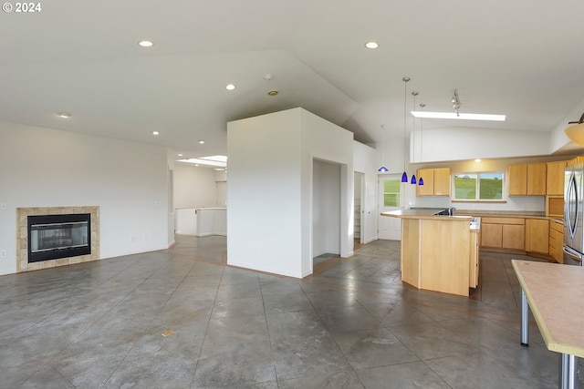 kitchen with light brown cabinets, recessed lighting, open floor plan, a center island, and stainless steel fridge