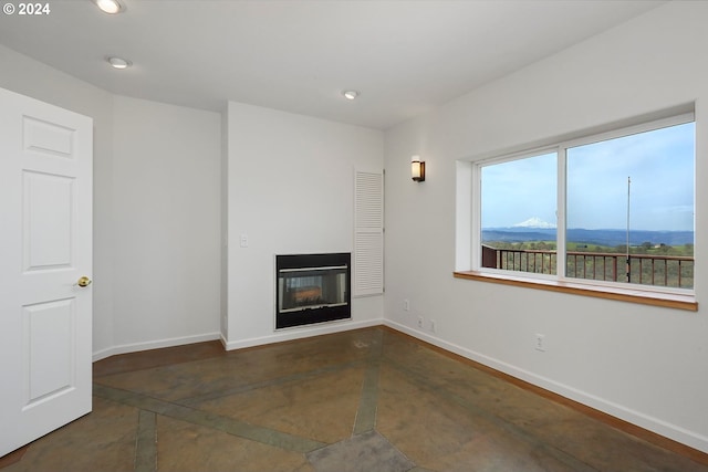 unfurnished living room featuring a glass covered fireplace, a mountain view, baseboards, and recessed lighting