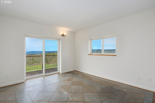 unfurnished room with light tile patterned floors, baseboards, and a mountain view