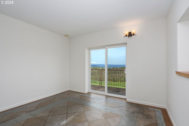 tiled empty room featuring a mountain view and baseboards