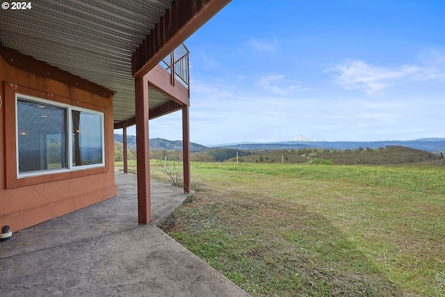 view of yard featuring a patio, a rural view, a balcony, and a mountain view