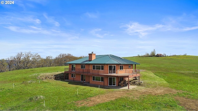 rear view of property with a yard, a chimney, and a wooden deck