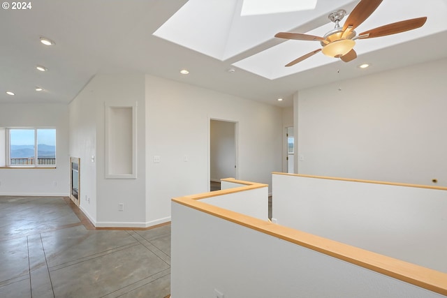 corridor with a skylight, baseboards, an upstairs landing, concrete floors, and recessed lighting