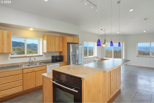 kitchen featuring a kitchen island with sink, light countertops, light brown cabinetry, black appliances, and a sink