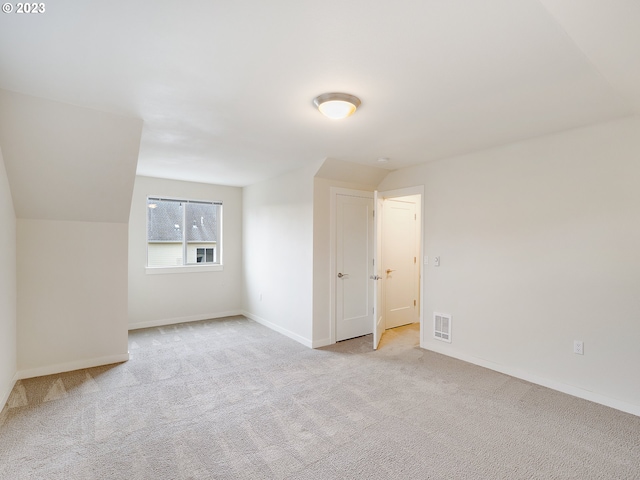 additional living space featuring light carpet