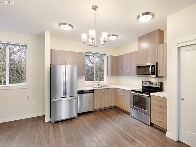 kitchen with plenty of natural light, light hardwood / wood-style flooring, pendant lighting, and appliances with stainless steel finishes