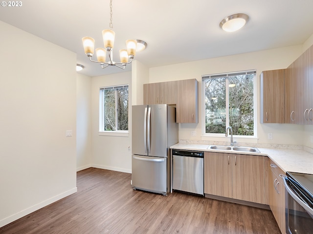 kitchen featuring pendant lighting, light wood-type flooring, stainless steel appliances, and sink