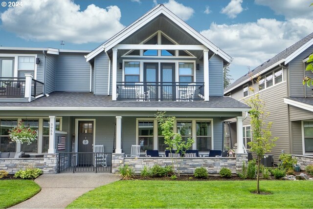 craftsman house with a balcony, a porch, and a front lawn