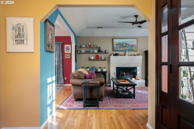 living room featuring a tile fireplace, ceiling fan, and wood-type flooring