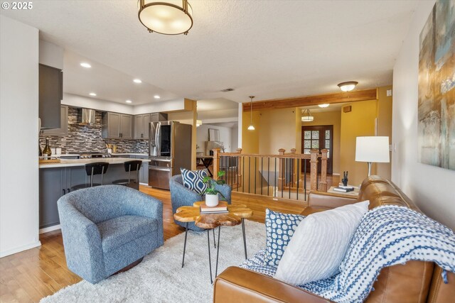 living room featuring vaulted ceiling, hardwood / wood-style flooring, ceiling fan, a textured ceiling, and a tiled fireplace