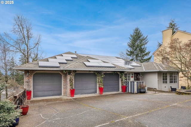 ranch-style home featuring solar panels, a garage, driveway, and a shingled roof