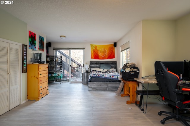 bedroom featuring multiple windows, a closet, light hardwood / wood-style flooring, and a textured ceiling