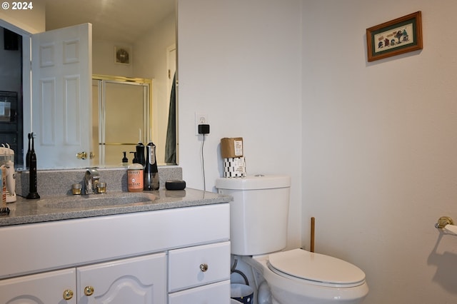 bathroom featuring vanity, toilet, and a shower with shower door