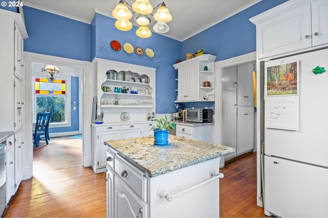 kitchen with white fridge, white cabinetry, light hardwood / wood-style flooring, and a kitchen island