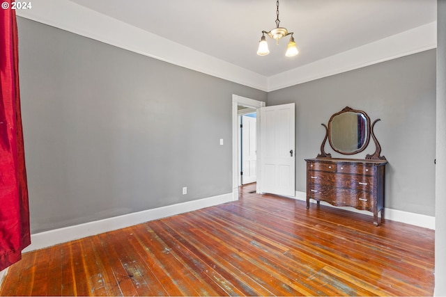 unfurnished room featuring wood-type flooring and an inviting chandelier