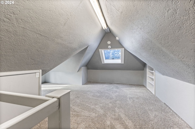 additional living space featuring vaulted ceiling, carpet flooring, and a textured ceiling