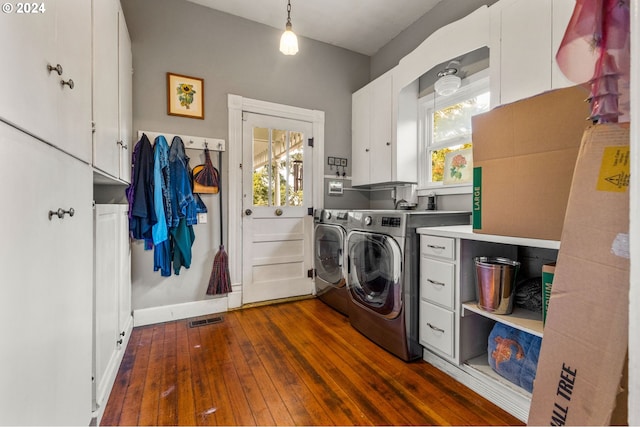 laundry area featuring washing machine and dryer, dark hardwood / wood-style floors, and cabinets