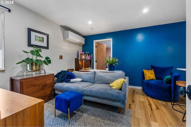 living room with a wall mounted AC and light hardwood / wood-style flooring