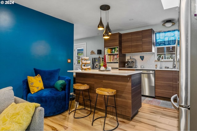 kitchen with light hardwood / wood-style floors, a healthy amount of sunlight, a breakfast bar area, and pendant lighting