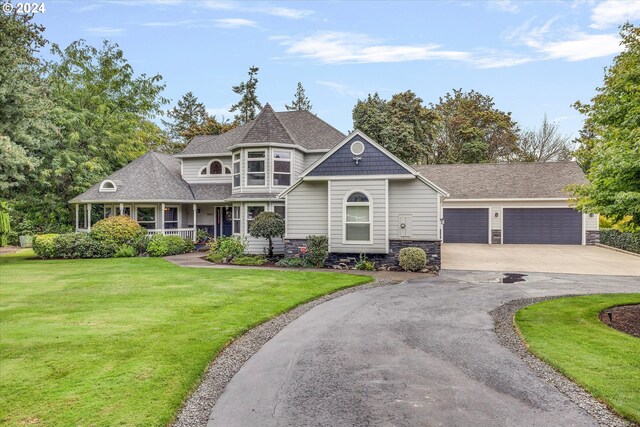 view of front of home with a porch, a garage, an outbuilding, and a front lawn