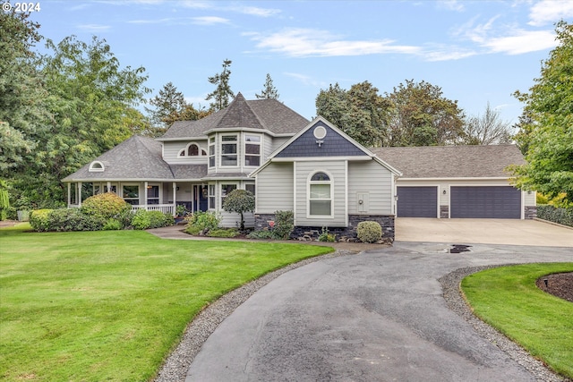 view of front of home featuring covered porch, concrete driveway, a front yard, a garage, and stone siding